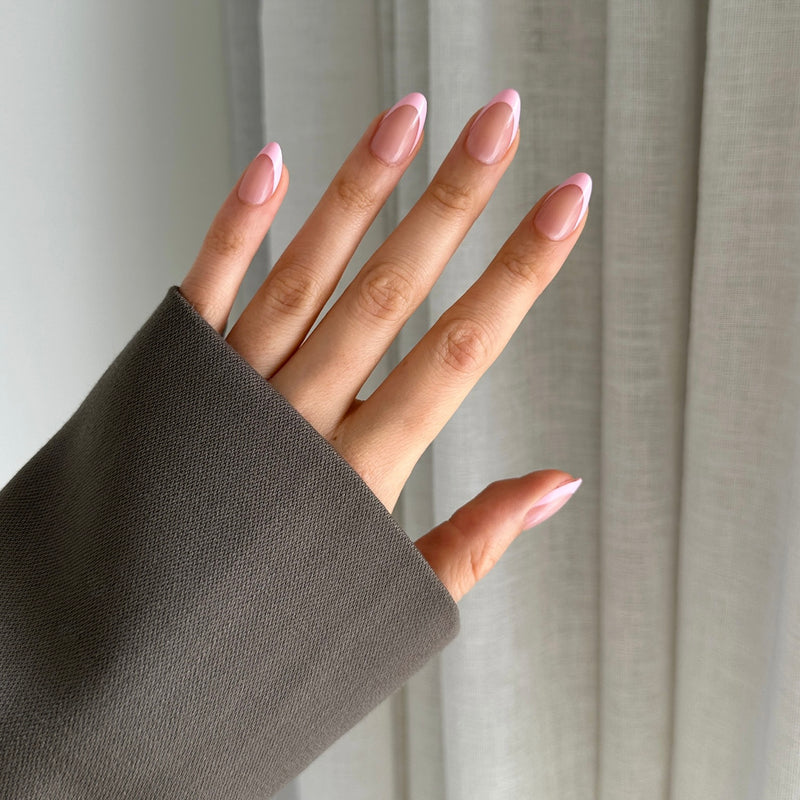 Hand with pink tip press on nails against a neutral background