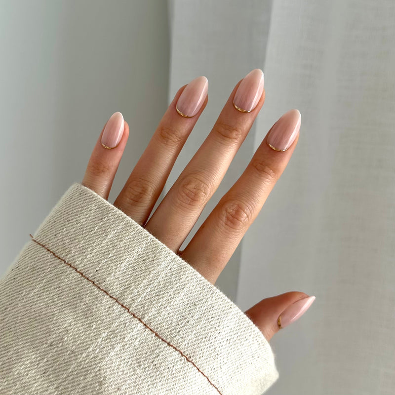 A person's hand with press-on nails showing a natural nail color.