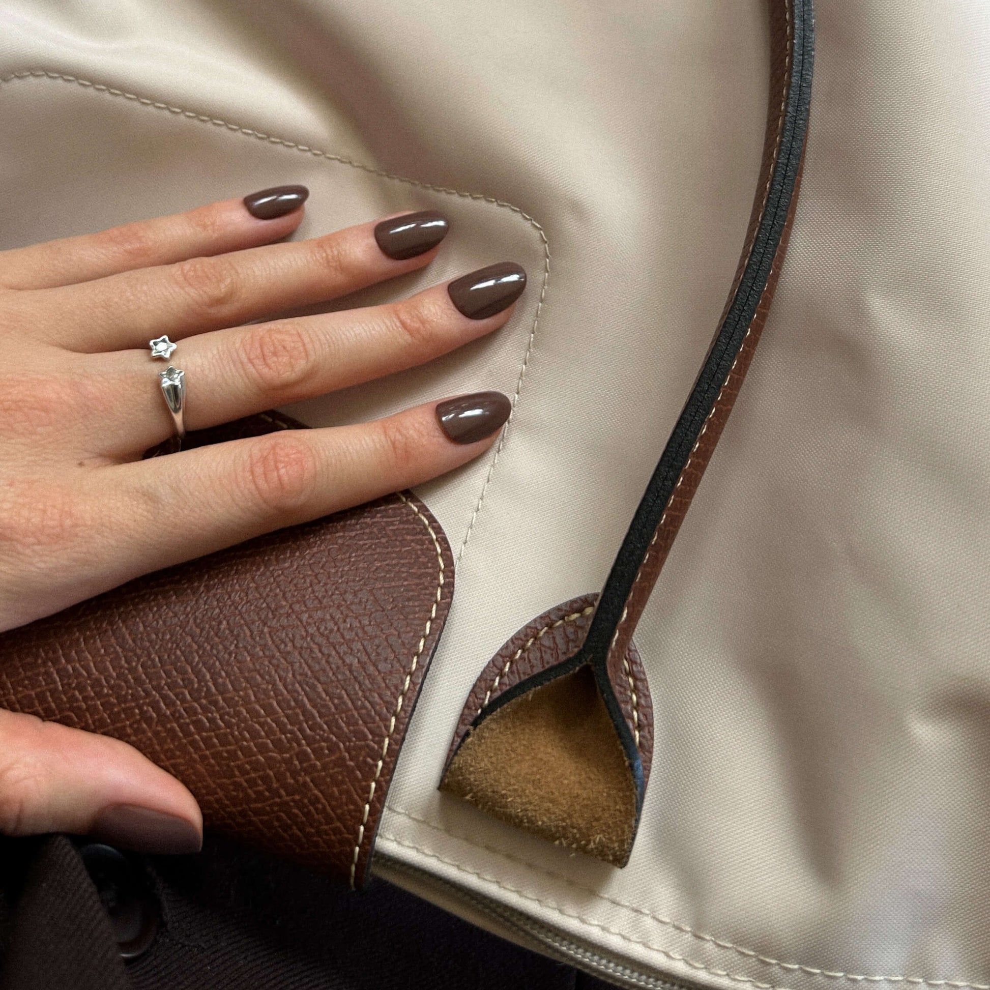 Hand with brown press on nails wearing a ring.