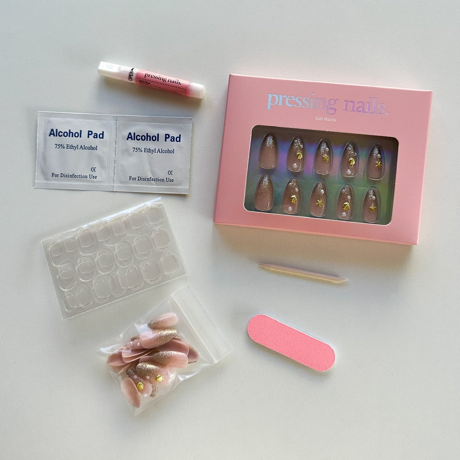 Collection of beauty products including a box of false nails, alcohol pads, and a nail file on a white surface.