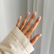 A person's hand with short, french-style press on nails.