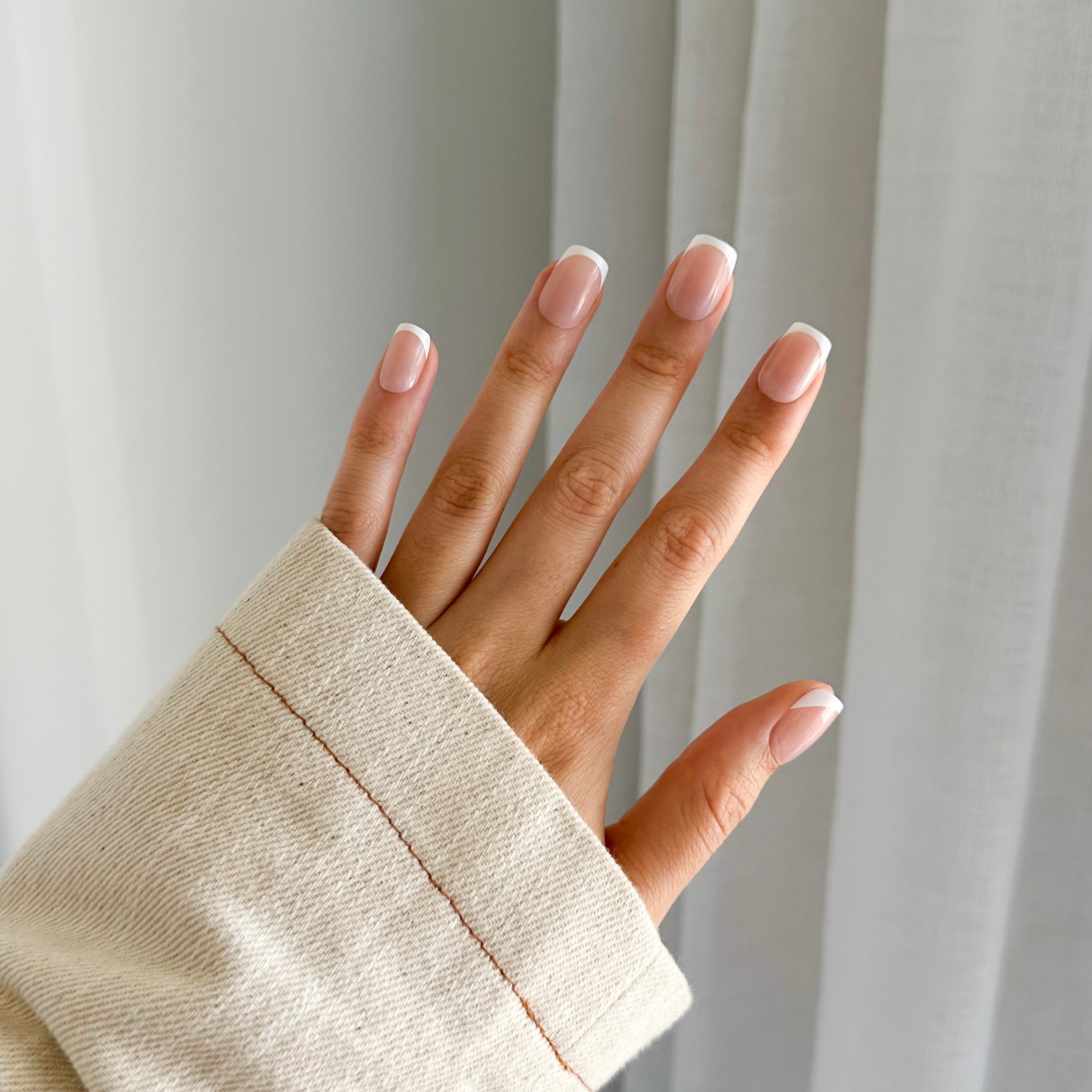 A person's hand with short, french-style press on nails.