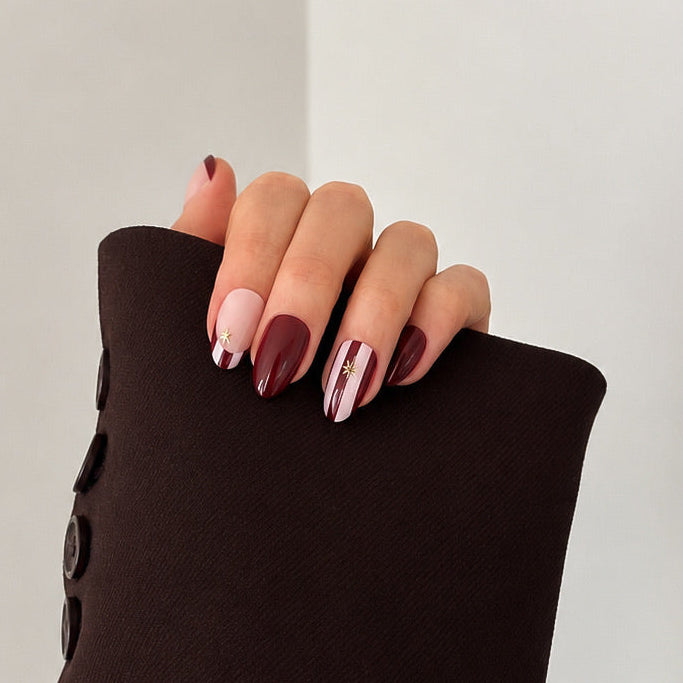A close-up of a hand with manicured nails resting on the cuff of a dark brown sleeveless top or dress, set against a minimalist off-white background.