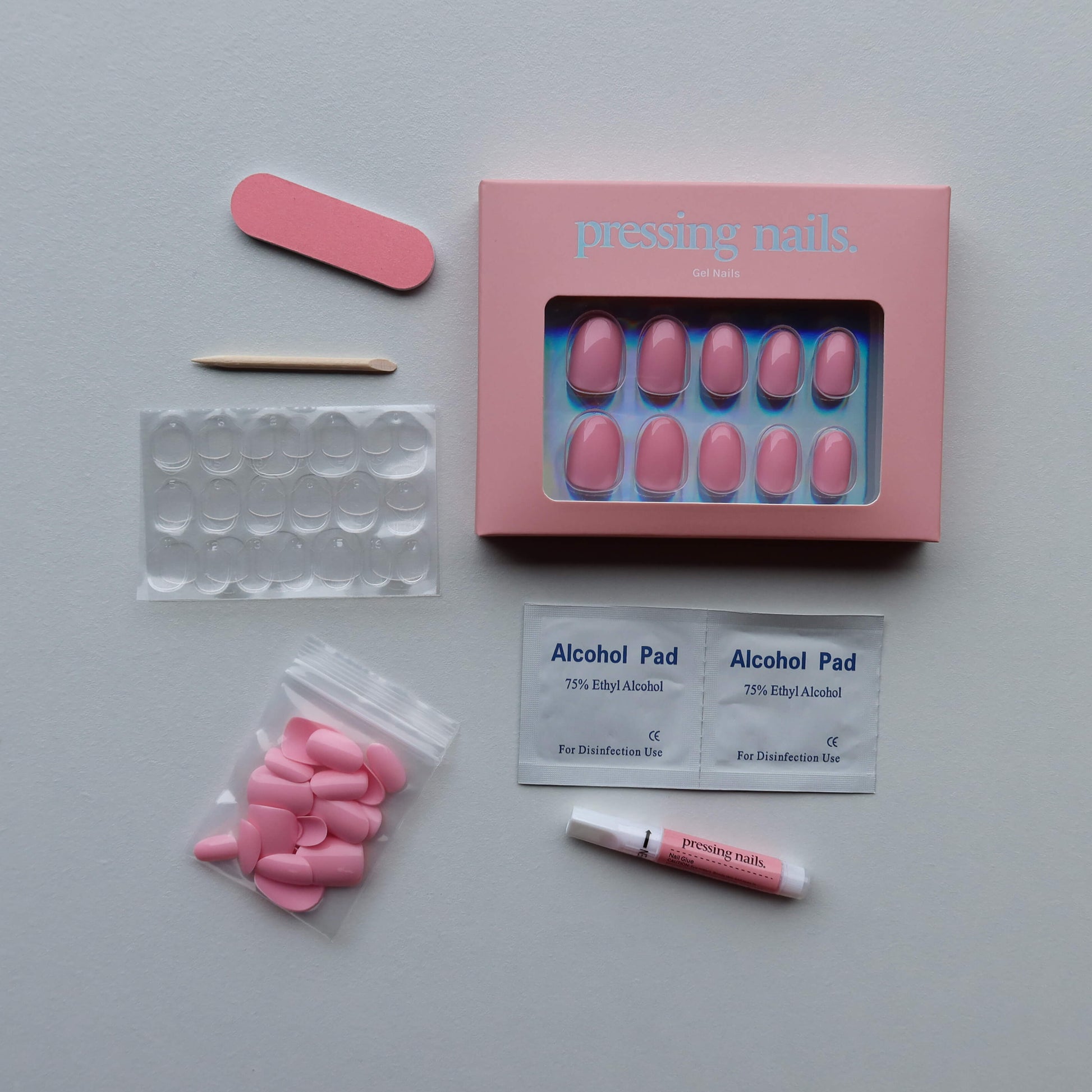 Pink press on nail kit with alcohol pads, and other supplies on a white backgrounds 