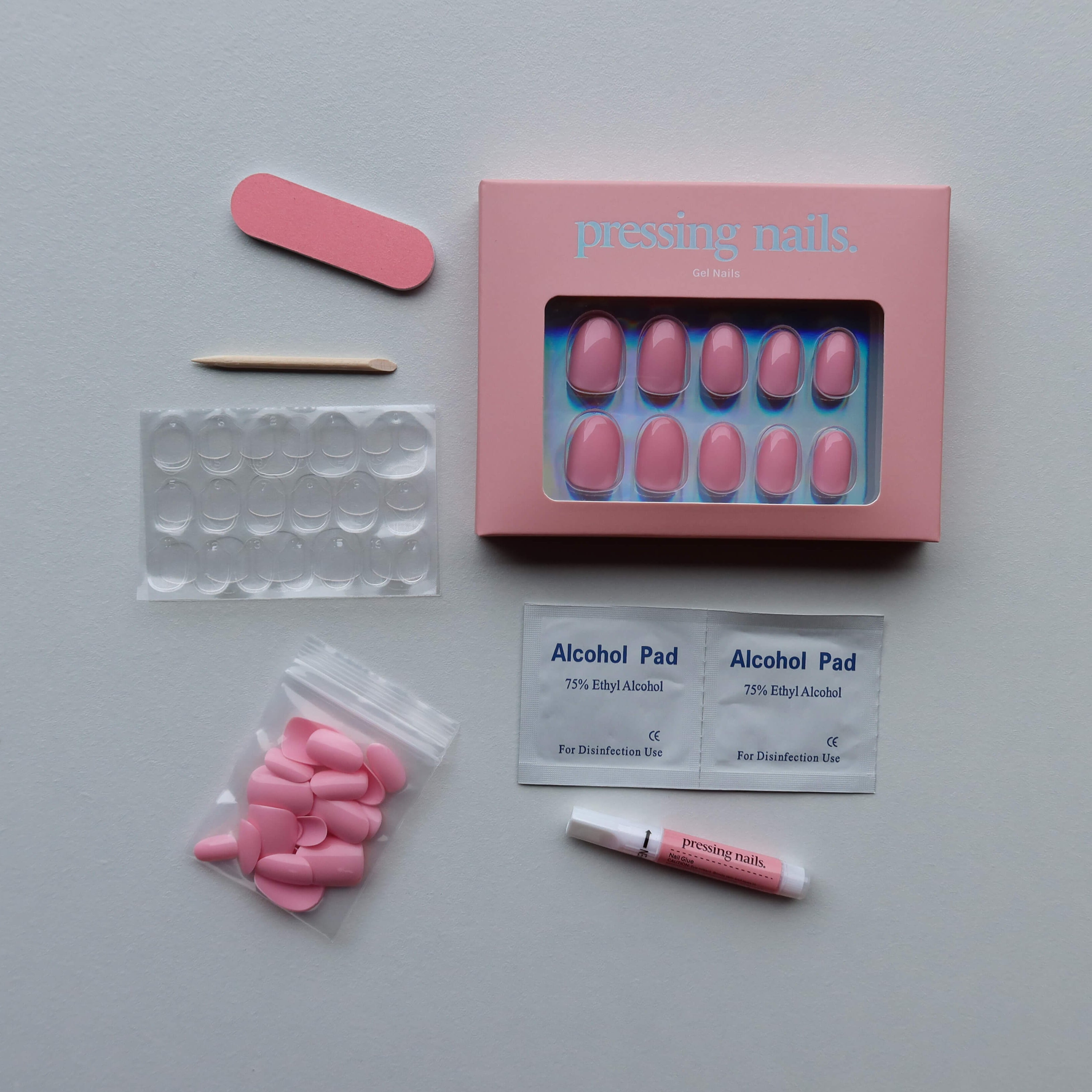 Pink press on nail kit with alcohol pads, and other supplies on a white backgrounds 