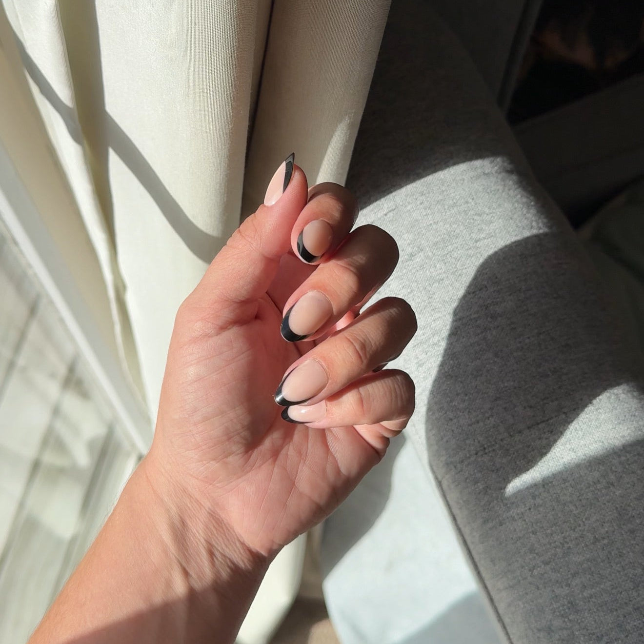 A hand with black-tipped gel press on nails.