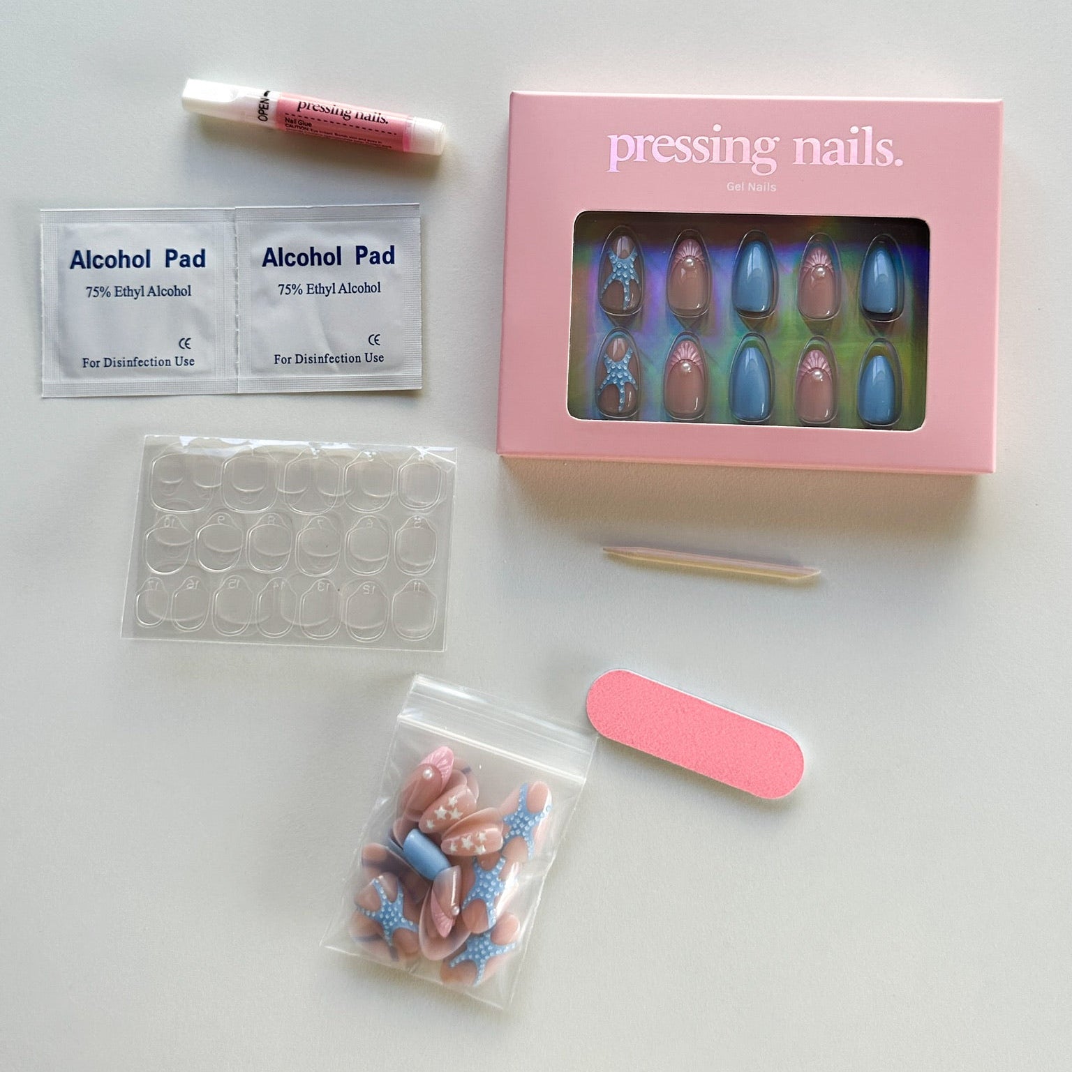 Manicure kit with press-on nails, alcohol pads, and a brush on a white background