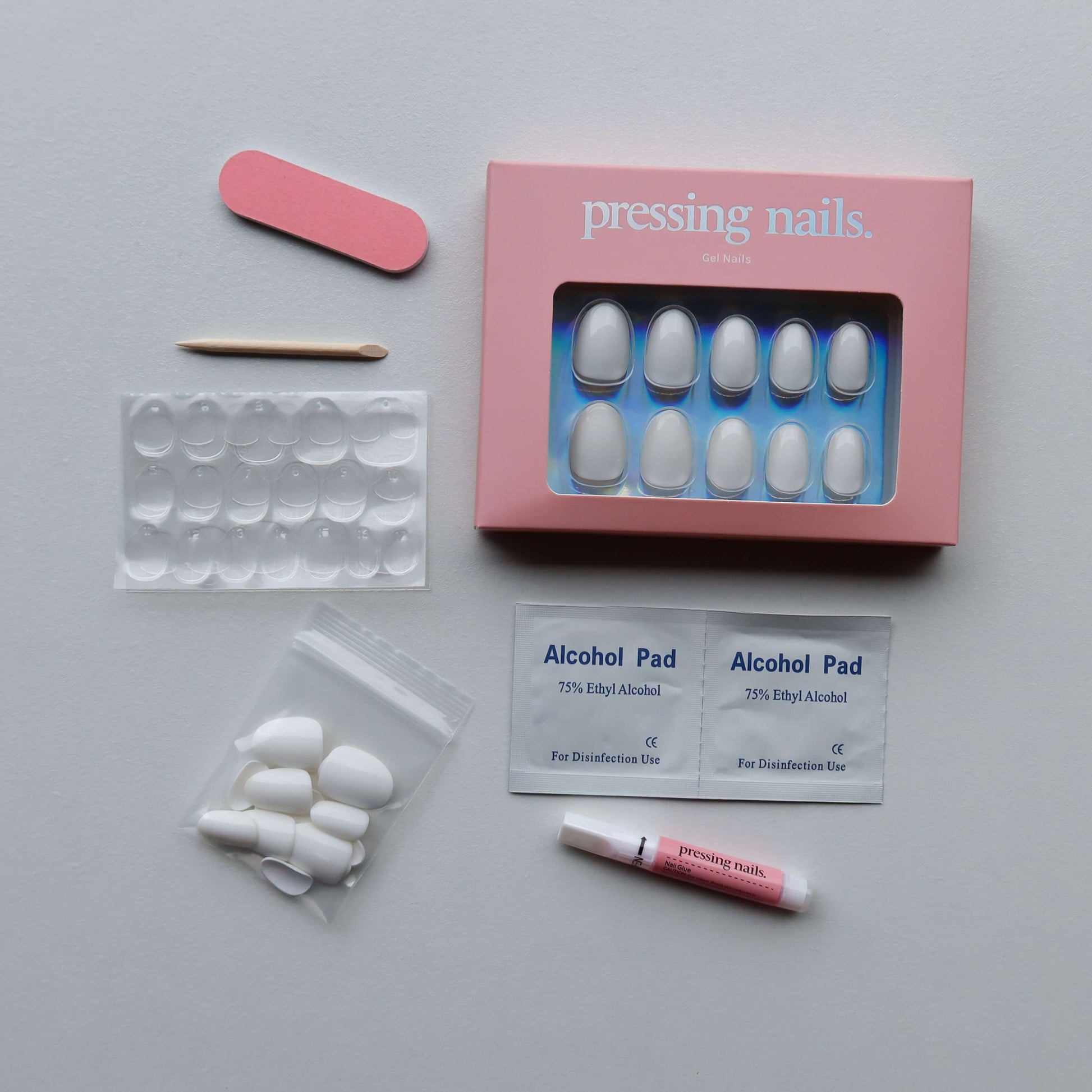 Manicure press on nail kit with nail tips, alcohol pads, and a pink box on a gray background