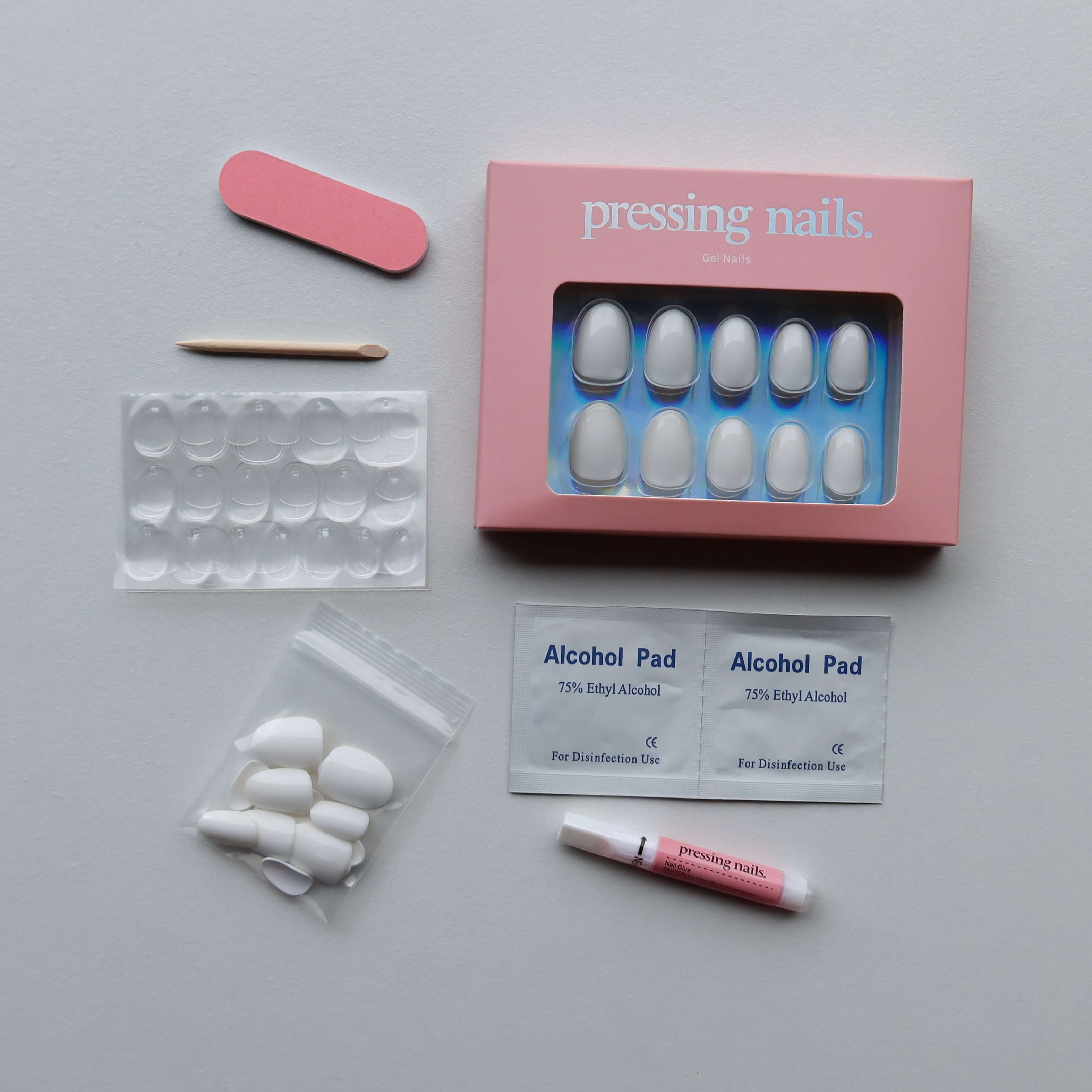 Manicure press on nail kit with nail tips, alcohol pads, and a pink box on a gray background