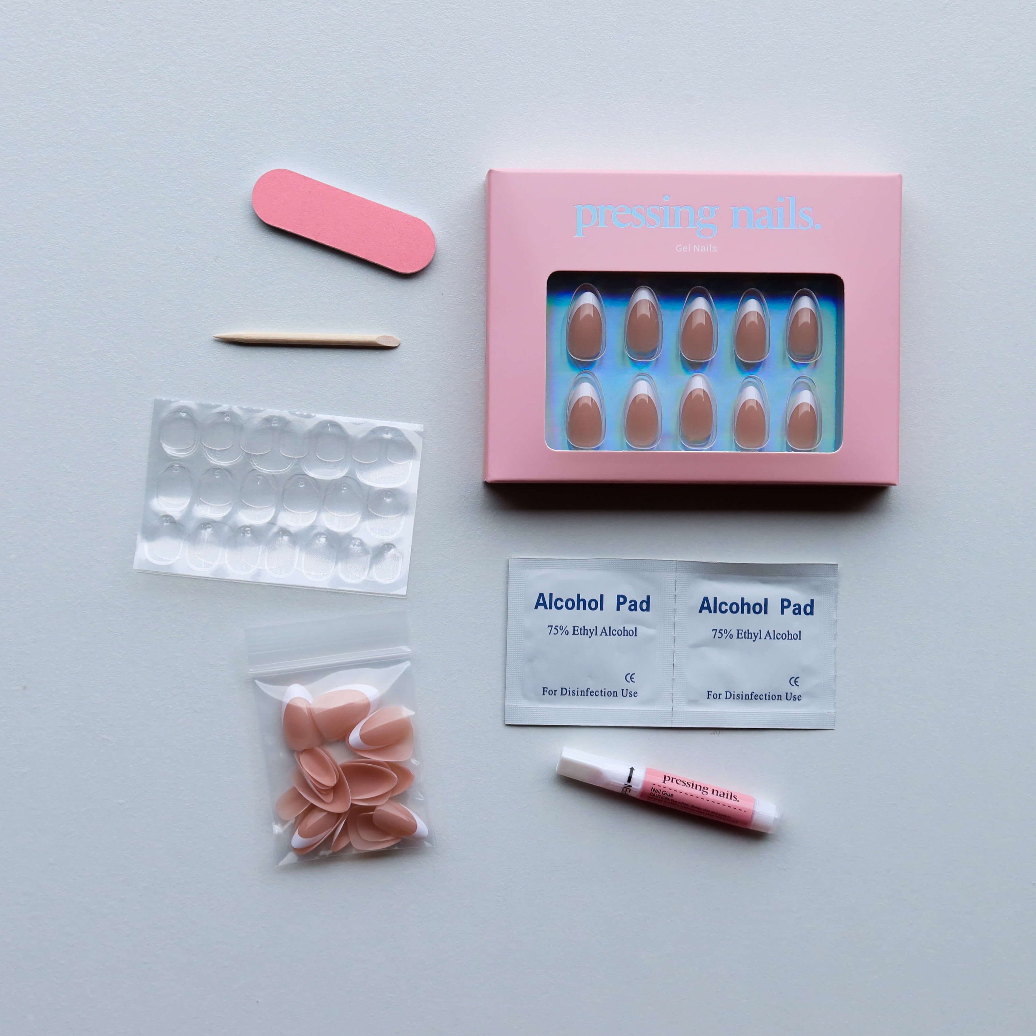 Flat Lay of a pressing nails kit, alcohol pads, and applicators on a white background