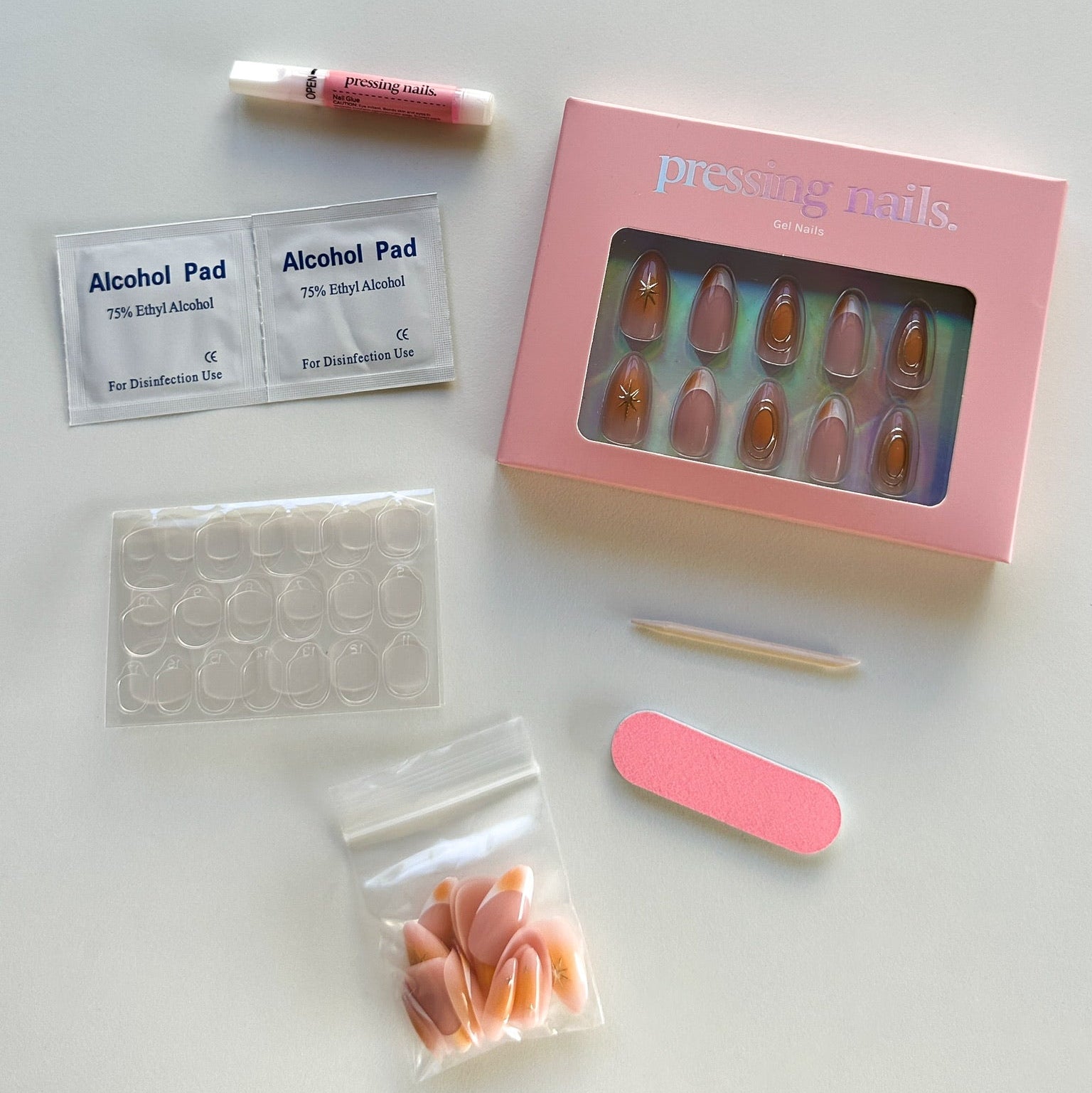 Manicure kit with nail tips, alcohol pads, and a pink box on a white surface