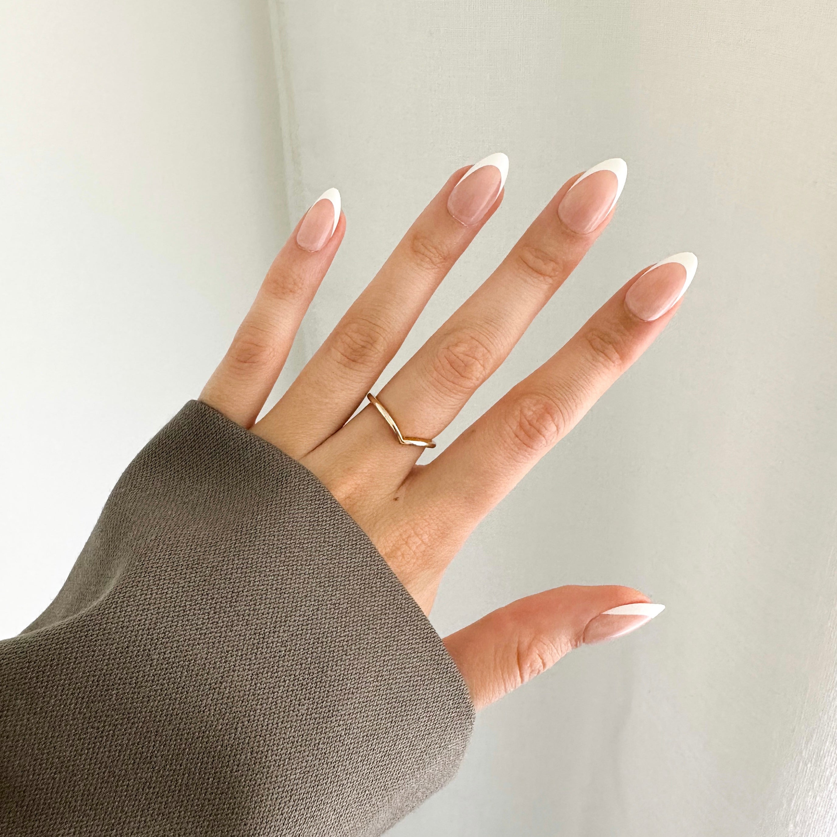 A hand wearing white tip french style press on nails that look high quality